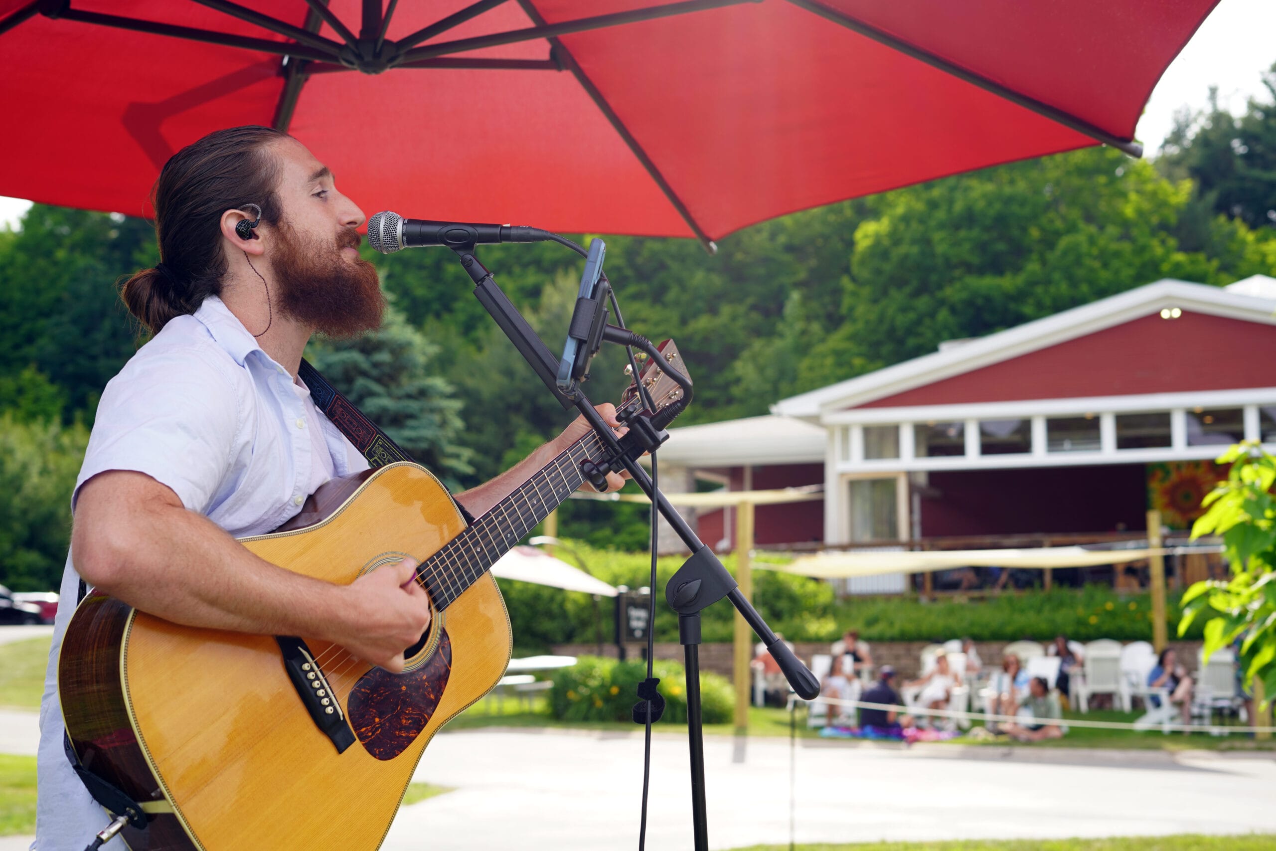 A person seated on a chair, skillfully playing an acoustic guitar, immersed in their music.