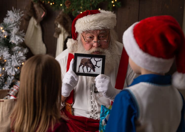 Santa showing a photo of a reindeer to two children.